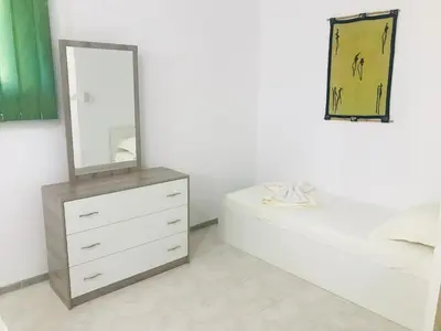 a white bedroom with a dresser and a mirror at PS Apartment / SunCoast Resort in Sveti Vlas