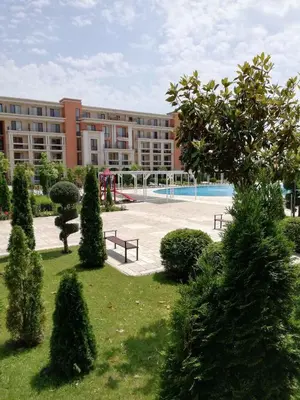 a building with a park with benches and trees at Private Apartment 49 in Prestige Fort Beach Hotel in Sveti Vlas