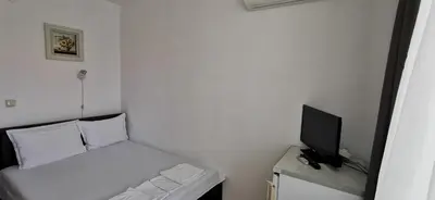 a small white room with a bed and a television at Къща за гости Слънчевият ъгъл - The sunny corner in Sozopol