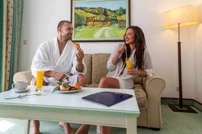 a man and a woman sitting on a couch eating food at Helena Park - Ultra All Inclusive in Sunny Beach