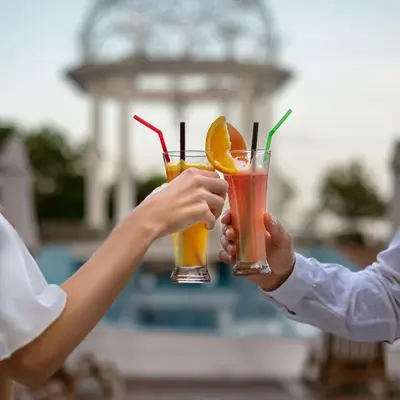 two people holding two cocktails in their hands at Helena Sands in Sunny Beach