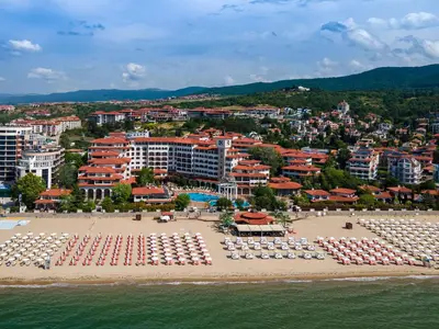 a beach with chairs and umbrellas and a city at Helena Sands in Sunny Beach