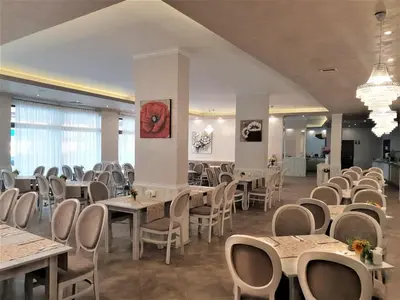 a dining room with tables and chairs and chandeliers at Grenada Hotel in Sunny Beach