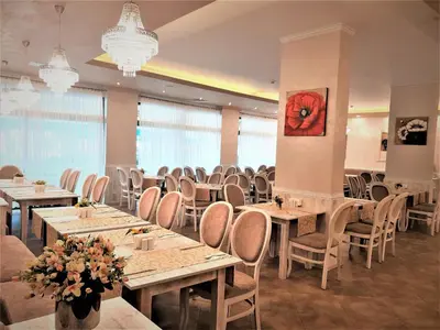 a dining room with tables and chairs and a clock at Grenada Hotel in Sunny Beach