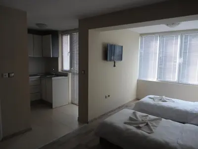 a bedroom with two beds and a kitchen with windows at Casa Luba Sunny beach in Sunny Beach