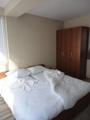 a large white bed in a bedroom with a wooden cabinet at Casa Luba Sunny beach in Sunny Beach