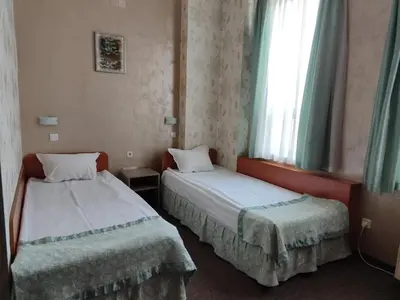 two beds in a small room with a window at Семеен Хотел 