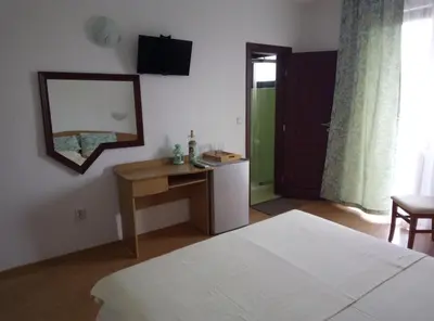 a bedroom with a bed and a table and a mirror at Family Hotel Bellehouse in Chernomorets