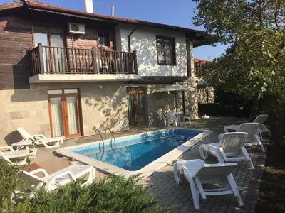 a villa with a swimming pool with chairs and a house at HillTop Villa in Burgas City