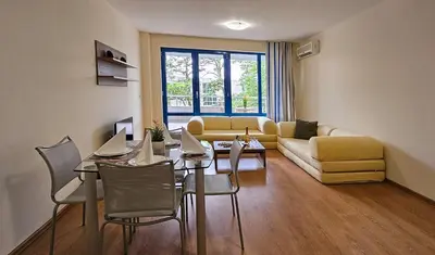 a living room with a table and a yellow couch at Excelsior Holiday Apartments Sunny Beach in Sunny Beach