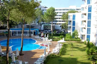 an outdoor swimming pool with lounge chairs and a building at Excelsior Holiday Apartments Sunny Beach in Sunny Beach