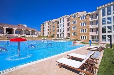 a swimming pool with two lounge chairs next to a building at Atia Resot in Chernomorets