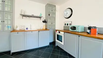 a kitchen with white cabinets and a clock on the wall at APARTELLO Modern Apartment - Balkan Breeze 7 in Sunny Beach