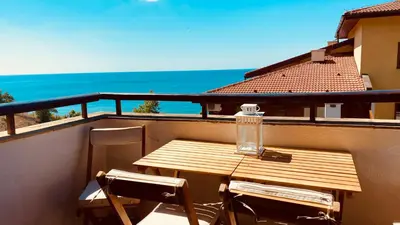a wooden table and chairs on a balcony with the ocean at APARTELLO Modern Apartment - Garden of Eden in Sveti Vlas