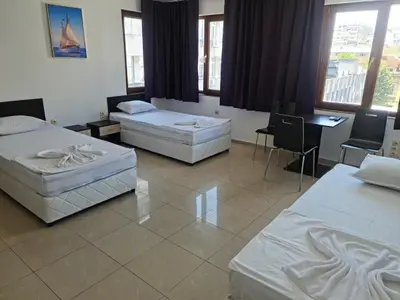 a room with three beds and a table and chairs at СТАИ ЗА ГОСТИ ХАН КРУМ in Burgas City