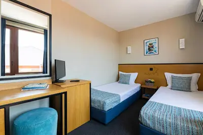 a room with two beds and a desk and a tv at Hotel Albatros New Town in Sozopol