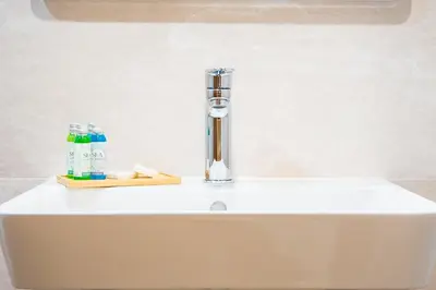 a white sink with a toothbrush and a toothbrush holder at Hotel Albatros New Town in Sozopol