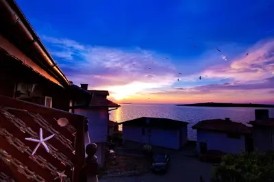 a sunset over a body of water with houses at Hotel Albatros Old Town in Sozopol