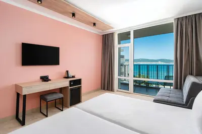 a bedroom with a bed and a desk with a television at Festa Panorama Hotel in Nesebar