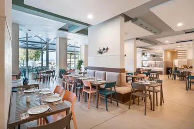 a dining room with tables and chairs and windows at Festa Panorama Hotel in Nesebar