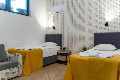 a room with two beds with yellow sheets and a chair at Family Hotel LAXO in Obzor