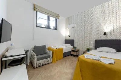 a room with two beds and a chair and a tv at Family Hotel LAXO in Obzor