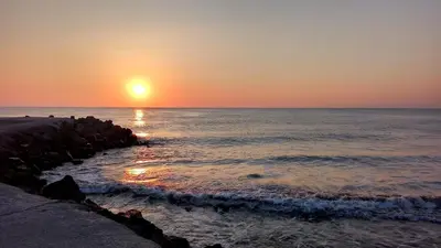 a sunset over the ocean with a rocky beach at Aivazovsky Park Anchialos H14 in Pomorie