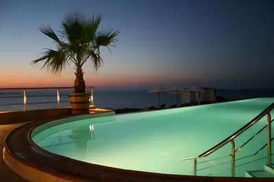 a swimming pool with a palm tree and the ocean at Apartments 