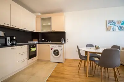 a kitchen with a table and a washing machine at By The Cliffs apartments in Byala