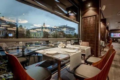a restaurant with tables and chairs and a large window at Hotel Bulgaria in Burgas City