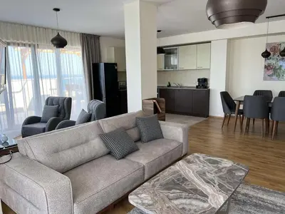 a living room with a couch and a kitchen at Penthouse at White Cliffs in Byala