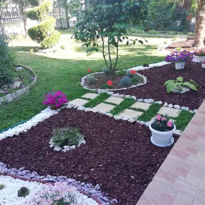 a garden with flowers and a tree in the middle at Albatros 2 Family Hotel in Kiten