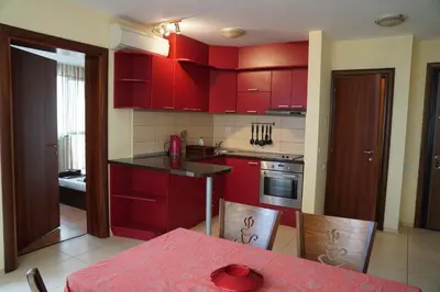 a kitchen with red cabinets and a red table and chairs at Apartments Paskalina in Byala