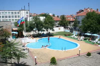 a large swimming pool with people sitting around it at хотел Централ in Sozopol