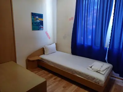 a small bed in a room with blue curtains at хотел Централ in Sozopol
