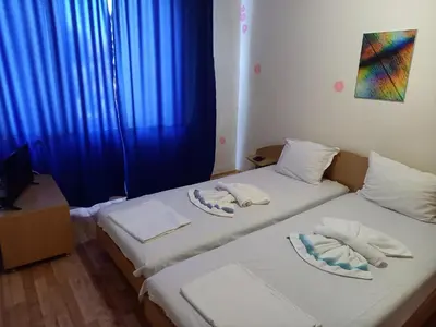 two twin beds in a room with blue curtains at хотел Централ in Sozopol
