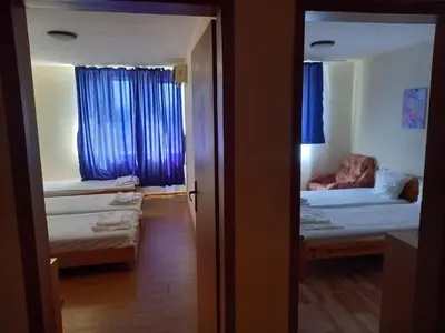 a room with two beds and a bedroom with blue curtains at хотел Централ in Sozopol