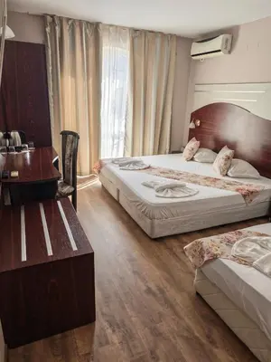 a hotel room with two beds and a desk at Palma in Burgas City