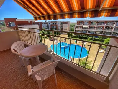 a balcony with a table and chairs and a swimming pool at Nessebar Fort Club Apartment 226 in Sunny Beach