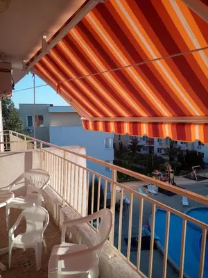 a balcony with a patio umbrella and chairs and a pool at Nessebar Fort Club Apartment 226 in Sunny Beach