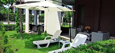 two white chairs and an umbrella in the grass at Diamond Palace in Sunny Beach