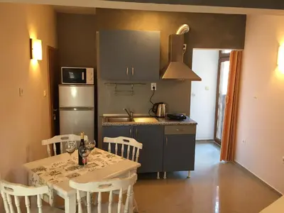 a kitchen with a table and chairs and a refrigerator at Guest House Afrodita in Chernomorets