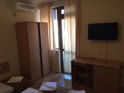 a room with a television and a desk with a cabinet at Guest House Afrodita in Chernomorets