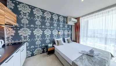 a bedroom with a large bed with blue and white wallpaper at Briz Beach Apartments in Sunny Beach