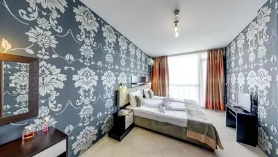 a bedroom with a bed with blue and white wallpaper at Briz Beach Apartments in Sunny Beach