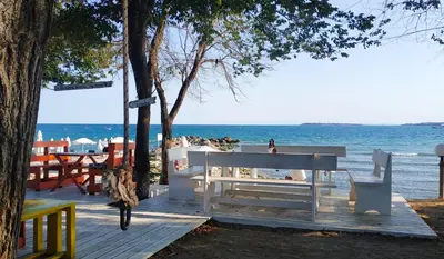 a white bench sitting next to the beach at New Line Village Apartments in Sunny Beach