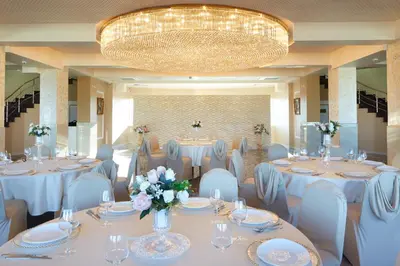 a banquet hall with white tables and chairs and a chandelier at Planeta Hotel & Aquapark FREE Beach Access - ULTRA All Inclusive in Sunny Beach