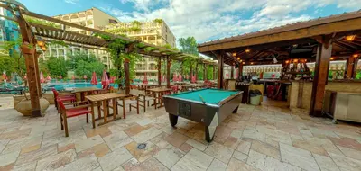 a pool table in a patio with tables and chairs at Mena Palace Hotel - All Inclusive in Sunny Beach