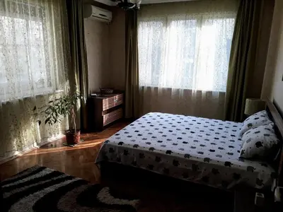 a bedroom with a bed and two windows at Family style, main street, 20 minutes from the sea in Burgas City