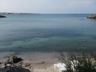a beach with two white chairs and the water at Villa Via Pontica in Sozopol